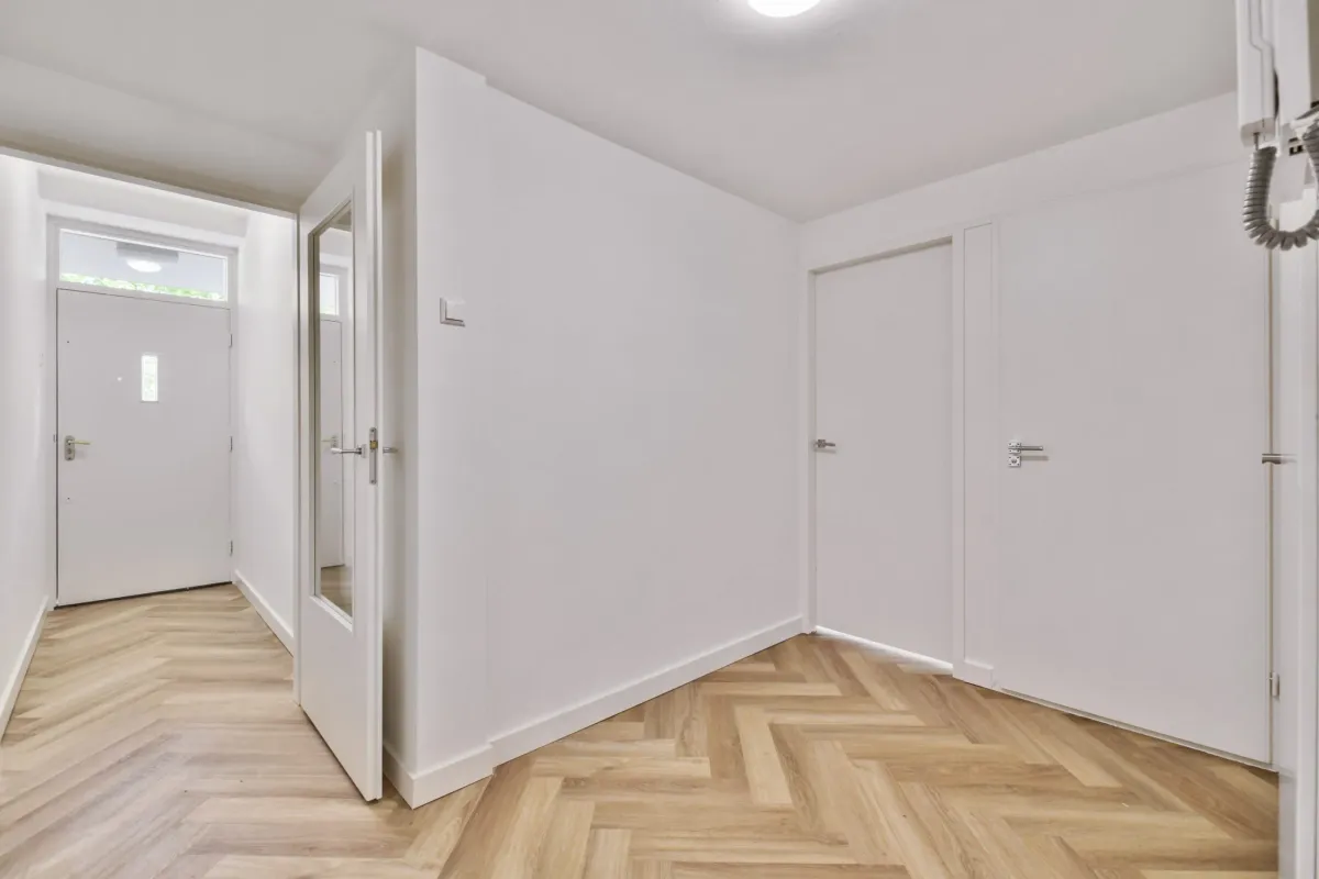 Interior hallway with white walls and light wood herringbone flooring